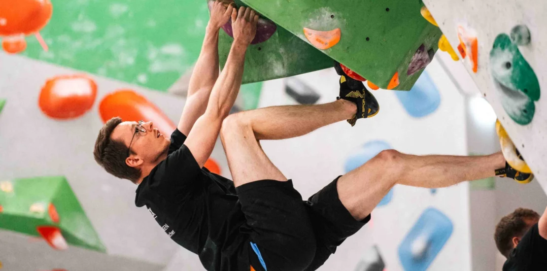 Eine männliche Person, die an einer Boulderwand beim BREDEX Boulder Day bouldert.