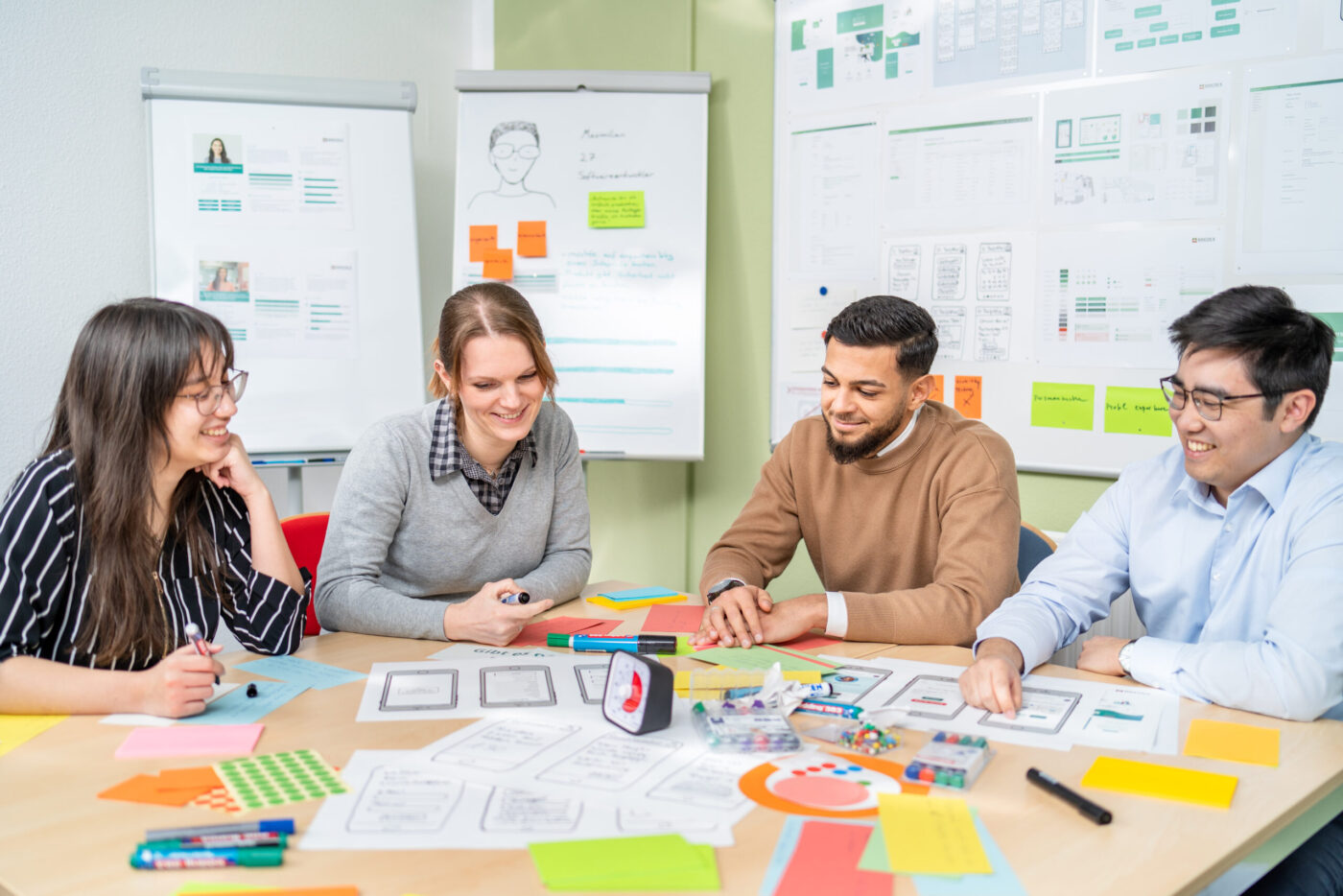 Eine Gruppe von Personen, die gemeinsam an einem Tisch sitzen. Vor ihnen liegen verschiedene Unterlagen ausgebreitet.