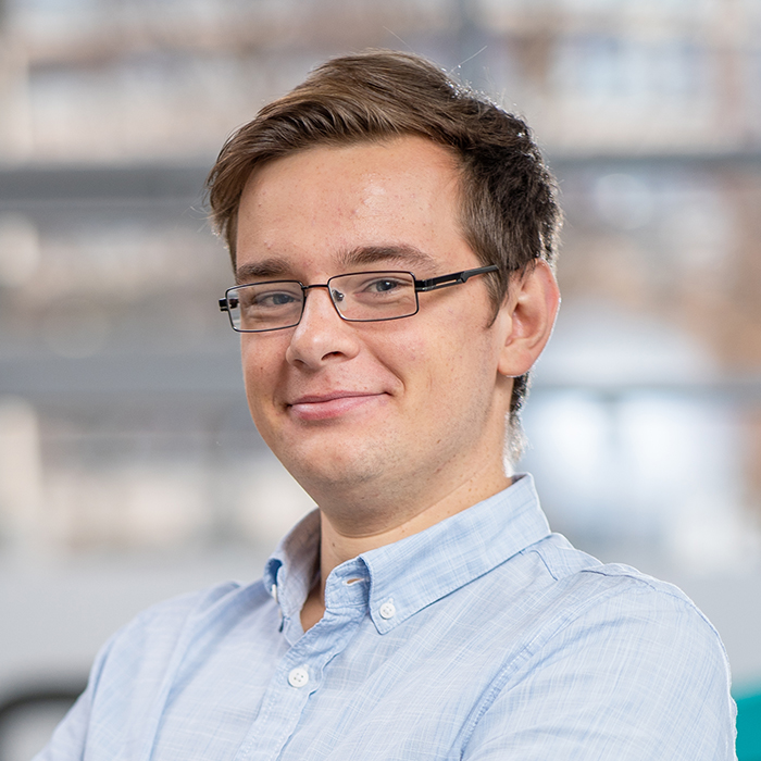 Trainer Christian Rucinski von BREDEX. Ein junger Mann mit braunen Haaren und einer eckigen Brille.