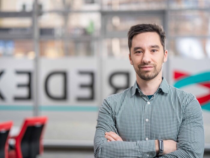 Trainer Benjamin Haederich von BREDEX. Ein junger weißer Mann mit kurzen, braunen Haaren und einem Bart.