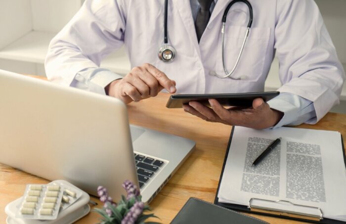 Arzt mit Tablet und Laptop – digitale Datenverwaltung im Gesundheitswesen