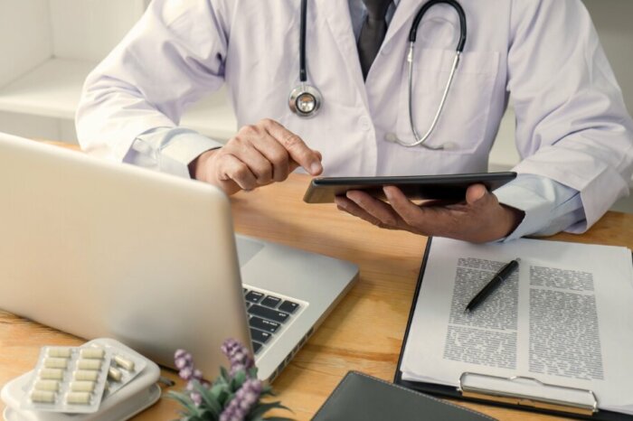 Arzt mit Tablet und Laptop – digitale Datenverwaltung im Gesundheitswesen